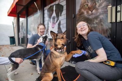 Two people with two dogs, one dog has his paw on the person's hand