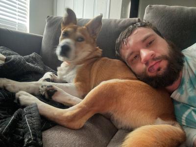 Wiley the dog cuddling with his adopter on a couch