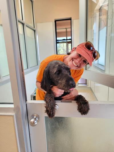 Credit One volunteer smiling and hugging a dog whose paws are on the top of a half door