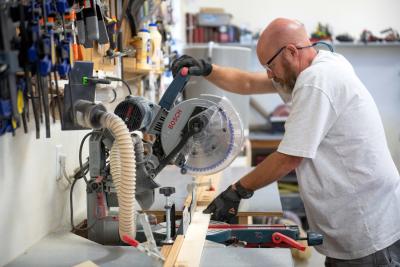 Volunteer Curtis McIff using a saw to cut wood to make the chairs