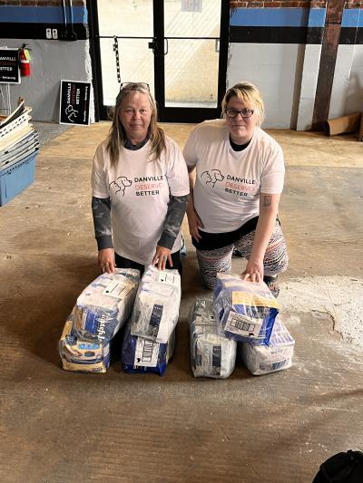 Two people with Danville Deserves Better with bags of pet food