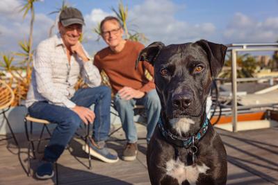 Bud the dog and his two adopters outside on a deck