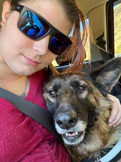 Selfie of Morgan wearing sunglasses next to Merlot the dog, who is lying with her head against Morgan's chest
