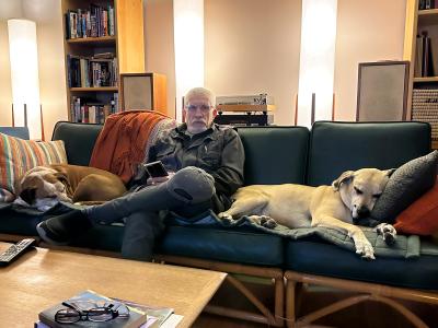 Cliff sitting on a couch with Yogi and Tank the dogs