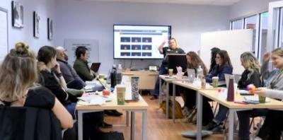 A group of people gathered around a table watching a presentation