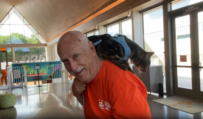 Allen Burkhart wearing an orange shirt with Eeyore the cat on his shoulder