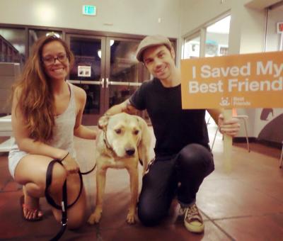 Erik Smith holding a 'I saved my best friend' sign, with another person and Nash the dog