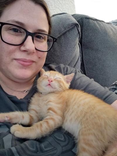 Jennifer Ronzello with a sleeping orange tabby kitten on her