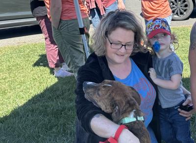Person sitting on the ground with a child and a dog