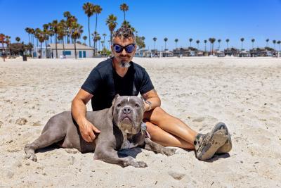 Person on a beach with hugging a dog