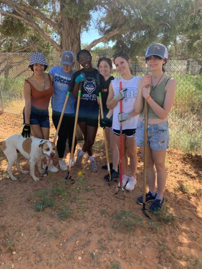 Girl Scout Troop 1019 with work tools volunteering at Best Friends Animal Sanctuary, alongside a dog