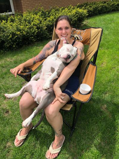 Person sitting in a chair outside with Poptart the dog lying asleep on her