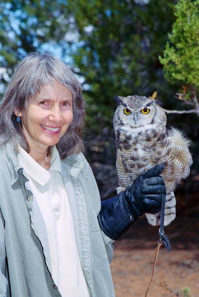 Vintage photo of Sharon St. Joan smiling and holding an owl on her gloved hand