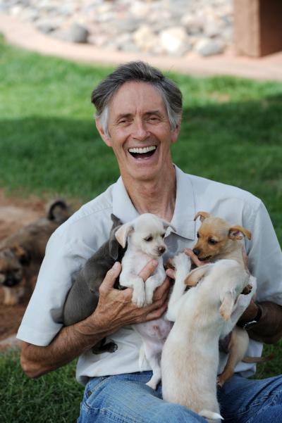 Gregory Castle smiling and holding a litter of puppies