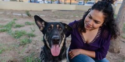 Woman in purple top sitting next to German Shepherd dog