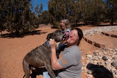 Legion the dog giving an enthusiastic kiss to a smiling person