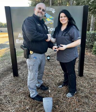 Captain Wyatt and Naomi Jenkins shaking hands in front of a sign
