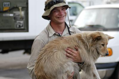 Best Friends employee Ethan smiling and carrying a dog