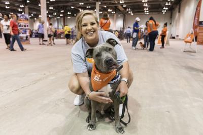 Smiling person hugging a dog wearing an orange Best Friends bandana