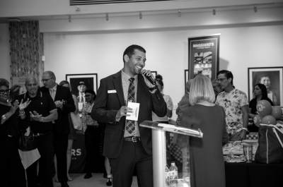 Lawrence Nicolas wearing a suit and speaking into a microphone