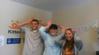 Lawrence Nicolas and two other people holding their hands up at their heads imitating a cat with an ear-tip