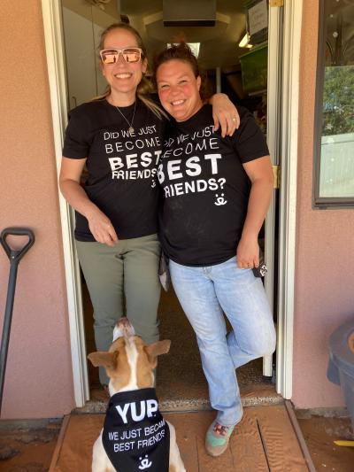 Jenny Franz with another person wearing Best Friends T-shirts, with a dog under them wearing a bandanna
