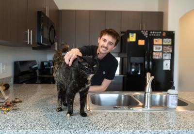 Emmalee the cat on a kitchen counter being petted by Isaac