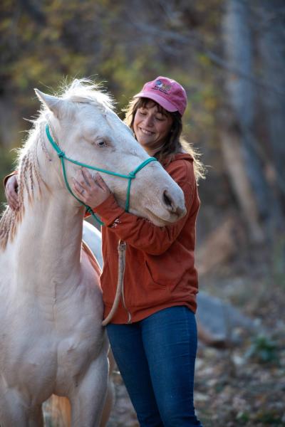 Person snuggling Jeff the horse outside in the woods