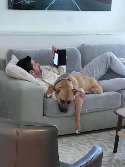 David Riley lying on a couch with Rex the dog