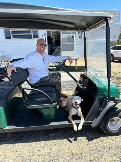 Jessie the dog and Joel in a golf cart