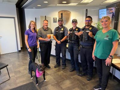 Staff from Bullhead City Animal Shelter standing in a line with a dog on a leash wearing a pink bandanna