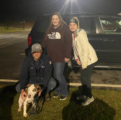 Skylar Clark and her parents outside at night with parvo survivor Mocha the dog