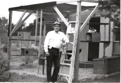 Black and white photo of Best Friends co-founder John Fripp standing in front of some construction of some cat housing