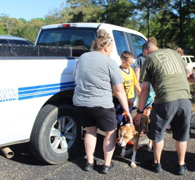 Three people petting a dog next to a Helping Hands Humane Society pickup truck