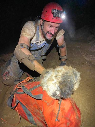 One of the cavers putting Abby the dog in a duffel bag to rescue her