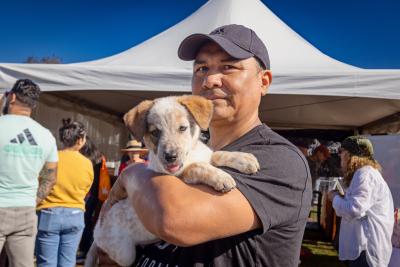 Person holding a puppy in front of a tent at the Best Friends Super Adoption