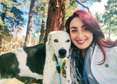 Photo of Laura with Skye the dog in front of some trees
