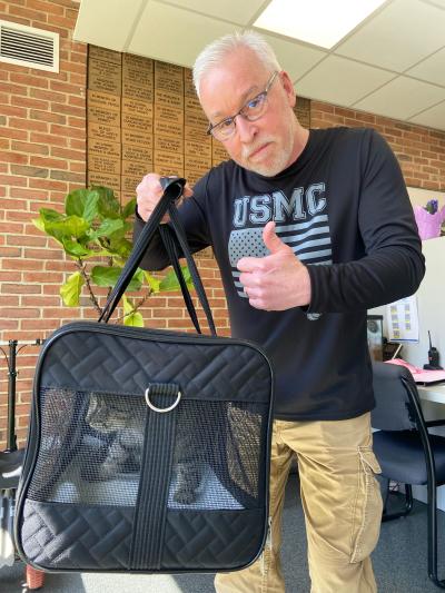 Person wearing a USMC shirt holding a cat in a soft-sided carrier