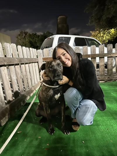 Smiling person posing next to Lucas Sinclair the dog inside a fence