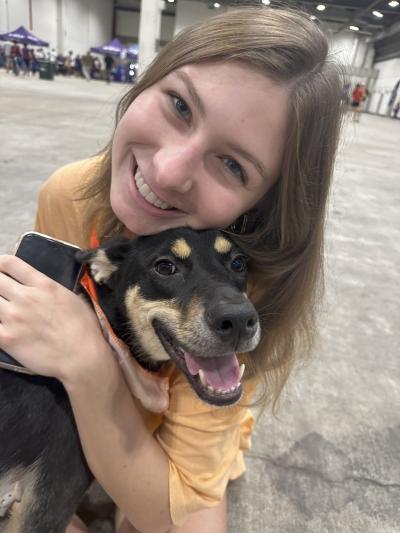 Smiling person hugging a happy black and tan dog
