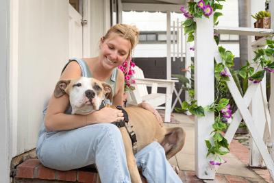 Person outside on a patio sitting with a large brown and white dog on her lap
