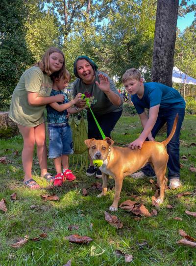 Mackenzie the dog with a ball in her mouth beside her new family