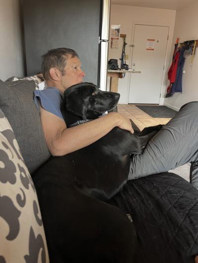 Mark Spragg sitting on a couch with a large black dog during a sleepover