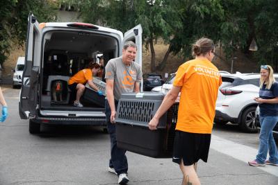 Mark Spragg helping another person carry a large kennel out of a van
