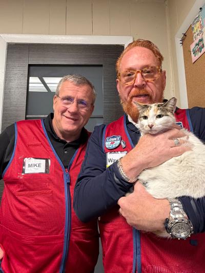 Wayne holding Francine the cat while standing next to Mike, both wearing their Lowe's vests