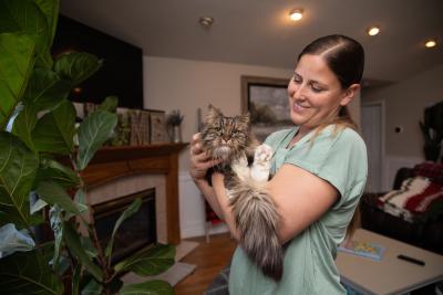 Chelsea, holding Mirage the cat, at home