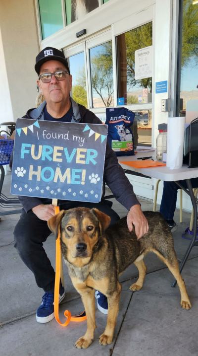 Jack the dog with his adopter, who is holding a sign that says, 'I found my furever home!'