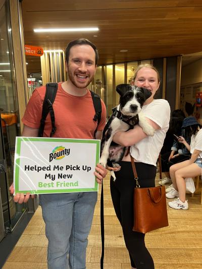 Two people holding a small dog and a sign at the National Adoption Weekend