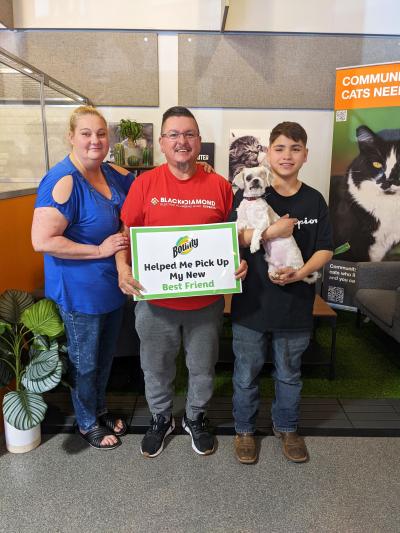 Three people holding a sign and dog with one eye at the National Adoption Weekend