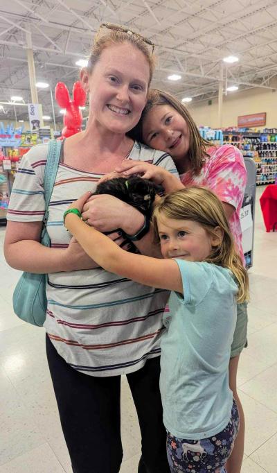 Happy family of three people (one adult and two kid) snuggling with their newly adopted kitten 